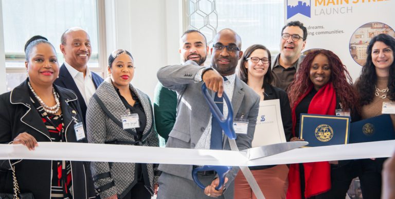 group of people in suits man in center cutting a ribbon