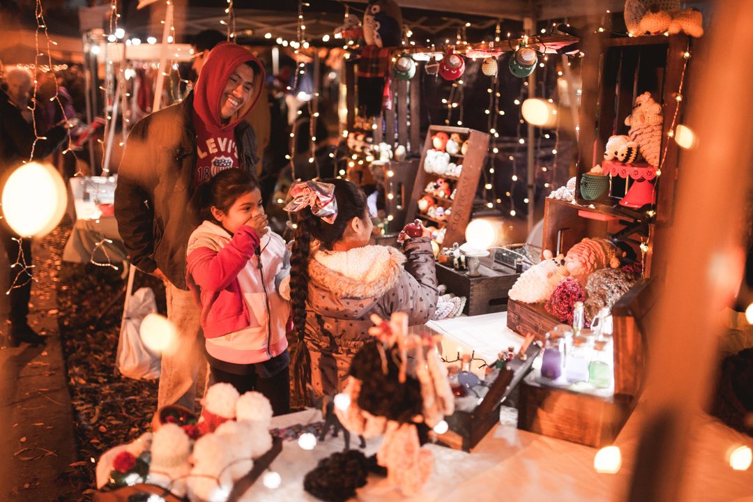 Smiling father and two daughters shopping in a vendors booth during the Holiday Stockmarket